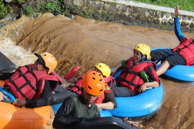 Neşeli bir atmosfer ve güneşli hava ile, Pandansari nehri üzerinde şamandıralar ile bir nehir akışı yaparken Turistler