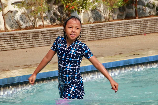 Een klein meisje spelen water in het zwembad — Stockfoto