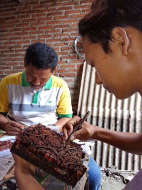 sanat işçileri, basit aletler ve manuel desenlerle bakırdan yapılmış pul kanting batik yaparken, Pekalongan Endonezya'da12 Nisan 2017