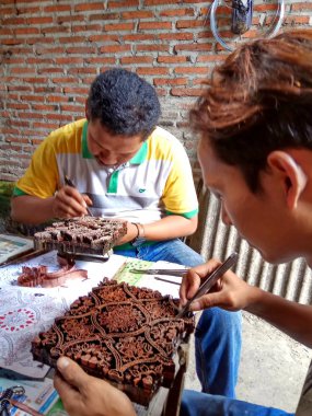 sanat işçileri, basit aletler ve manuel desenlerle bakırdan yapılmış pul kanting batik yaparken, Pekalongan Endonezya'da12 Nisan 2017