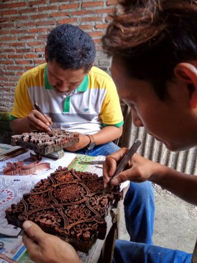 sanat işçileri, basit aletler ve manuel desenlerle bakırdan yapılmış pul kanting batik yaparken, Pekalongan Endonezya'da12 Nisan 2017
