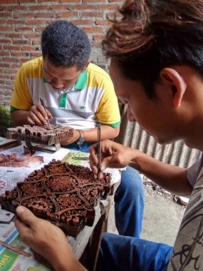 sanat işçileri, basit aletler ve manuel desenlerle bakırdan yapılmış pul kanting batik yaparken, Pekalongan Endonezya'da12 Nisan 2017