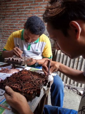 sanat işçileri, basit aletler ve manuel desenlerle bakırdan yapılmış pul kanting batik yaparken, Pekalongan Endonezya'da12 Nisan 2017