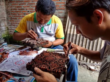 sanat işçileri, basit aletler ve manuel desenlerle bakırdan yapılmış pul kanting batik yaparken, Pekalongan Endonezya'da12 Nisan 2017