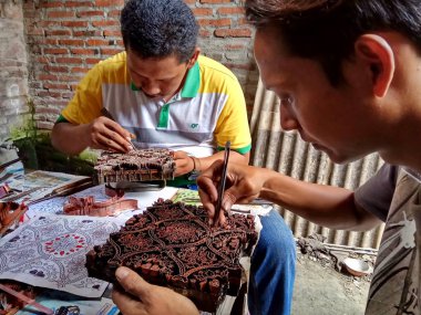 sanat işçileri, basit aletler ve manuel desenlerle bakırdan yapılmış pul kanting batik yaparken, Pekalongan Endonezya'da12 Nisan 2017