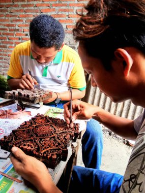 sanat işçileri, basit aletler ve manuel desenlerle bakırdan yapılmış pul kanting batik yaparken, Pekalongan Endonezya'da12 Nisan 2017