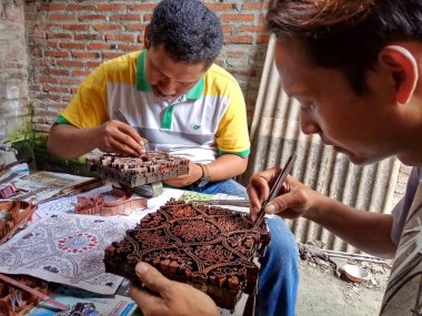 sanat işçileri, basit aletler ve manuel desenlerle bakırdan yapılmış pul kanting batik yaparken, Pekalongan Endonezya'da12 Nisan 2017