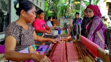 Lombok / Batı Nusa Tenggara-Endonezya'da geleneksel dokuma tezgahları kullanarak kumaş örerken Lombok'ta yaşayanlar, 24 Kasım 2016