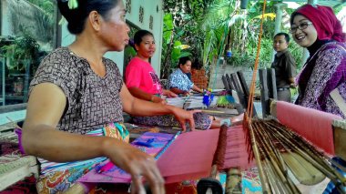 Lombok / Batı Nusa Tenggara-Endonezya'da geleneksel dokuma tezgahları kullanarak kumaş örerken Lombok'ta yaşayanlar, 24 Kasım 2016