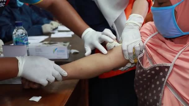 高齢者はコロナウイルス検査を行います 防護服を着た医者は血を引く 非侵襲性試験法 迅速なテストCovid Batang Indonesia 2020年5月27日 — ストック動画