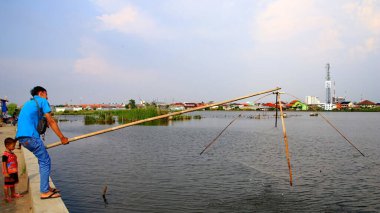  Odaklanamayan, bulanık seçici odak ve gürültü görüntüsü. Bir adam 14 Haziran 2020 'de Pekalongan Endonezya gölünde balık yakalamak için ağ kullanır.