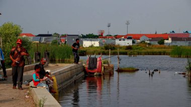 Odaklanamayan, bulanık seçici odak ve gürültü görüntüsü. Bir adam 14 Haziran 2020 'de Pekalongan Endonezya gölünde balık yakalamak için ağ kullanır.