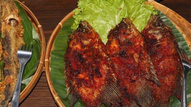 Muz yapraklı baharatlı kırmızı biberli ızgara balık. Geleneksel Endonezya mutfağı dumanlı aroma, canlı doku ve otantik Asya mutfağı sunumu.