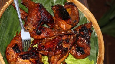 Bambu tabağında muz yapraklarıyla servis edilen soya soslu ızgara tavuk. Orijinal Asya mutfağı dumanlı aromalı, altın desenli ve geleneksel yemek tarzı..