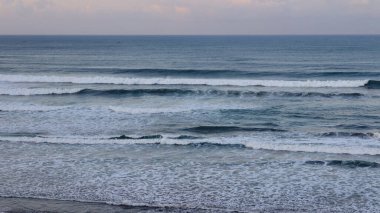 Huzurlu okyanus dalgaları kıyıda köpüklü sörf ve sakin ufuklarla kırılıyor. Seyahat, doğa, meditasyon, deniz manzarası, kıyı geçmişleri, yaz tatili ve çevre kavramları için mükemmel..