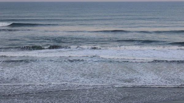Huzurlu okyanus dalgaları kıyıda köpüklü sörf ve sakin ufuklarla kırılıyor. Seyahat, doğa, meditasyon, deniz manzarası, kıyı geçmişleri, yaz tatili ve çevre kavramları için mükemmel..