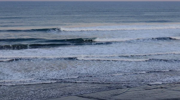 Huzurlu okyanus dalgaları kıyıda köpüklü sörf ve sakin ufuklarla kırılıyor. Seyahat, doğa, meditasyon, deniz manzarası, kıyı geçmişleri, yaz tatili ve çevre kavramları için mükemmel..