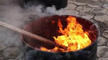 Alevlerle dolu metal bir fıçının içinde yanan ateş ve açık havada parlayan ısı. Enerji, hayatta kalma, sıcaklık, tehlike ve kamp konuları için mükemmel..