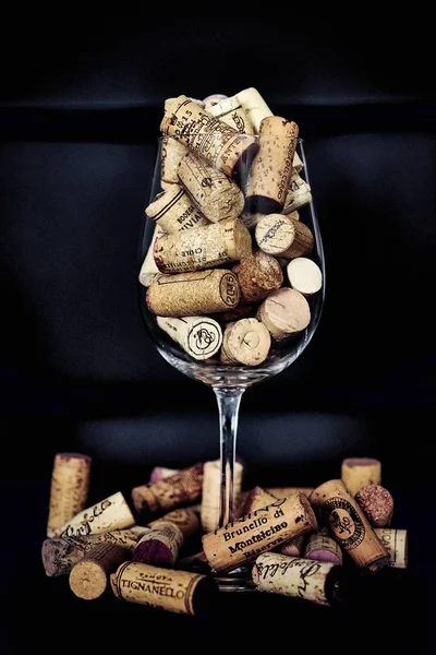 Corchos vertidos en una copa de vino sobre un fondo oscuro — Foto de Stock