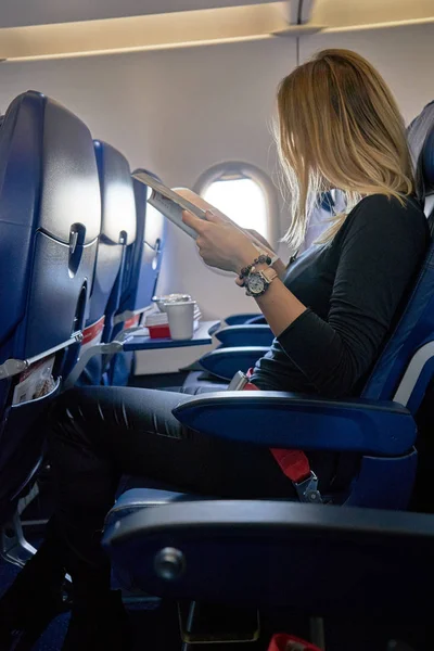 Mujer joven uso del teléfono móvil dentro del avión — Foto de Stock