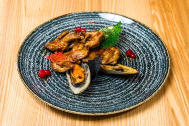 Midye ahşap bir masa üzerinde siyah bir plaka ile kızarmış kanatlar