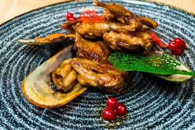 Midye ahşap bir masa üzerinde siyah bir plaka ile kızarmış kanatlar