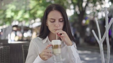 güneşli gün, yeşil ağaçların bir arka plan karşı bir restoran yaz oyun bir telefon ile güzel esmer iş kadını