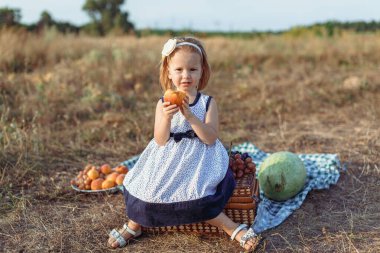 Sonbahar, küçük kızıl saçlı kız şeftali yer.