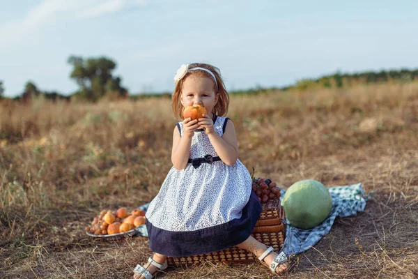 Autumn, little red-haired girl eats peach — Stock Photo, Image