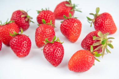 Beyaz arka plandaki parıltıdan birkaç çilek çıkartılır.