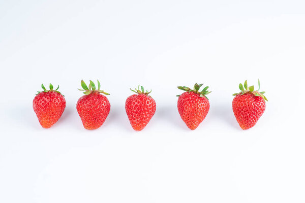five strawberry berries in a row on a white background
