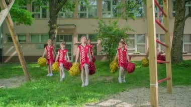 İlkokul kızları okul performansı için rutinlerini pratik ediyorlar. Okul bahçesinde dans ediyorlar..