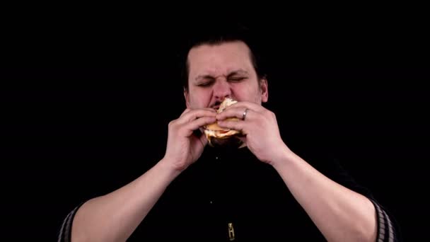 饥饿的年轻已婚男子试图咬到美味的汉堡包 上面装满了种子 里面装满了猪肉汉堡和羊奶酪 他咬了一小块 — 图库视频影像
