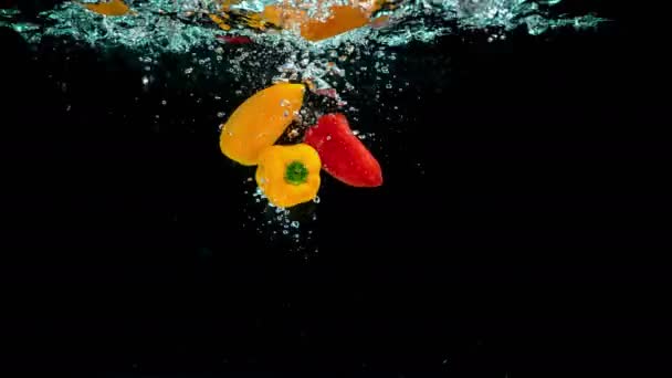 生和有机红色和橙辣椒优雅地落入新鲜水晶清澈的水盆 — 图库视频影像