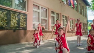 Küçük kızlar, ana çubuklarıyla rutin icra ediyorlar. Dışarıda dans ediyorlar..