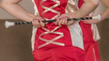 Kızlar performansları başladığında kalçalarını hareket ettirmeye başlıyorlar. Majorette coplarını arkalarında tutuyorlar..