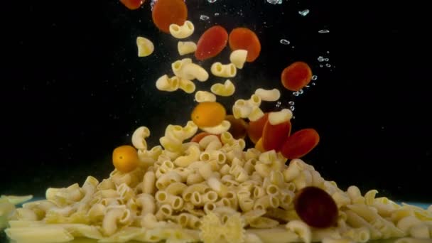 マカロニの異なる形状で満たされた沸騰した塩水とポット 小さな赤いトマトと曲がったマカロニが水に落ちる — ストック動画