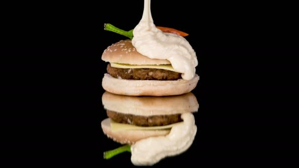 ハンバーガーは種子で覆われ ビーフバーガーとチーズで満たされ 白いソースを注ぎました パンの上の赤唐辛子 — ストック動画