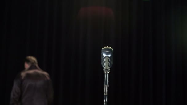 性感的男歌手在黑色离开舞台后 成功表演与麦克风在前景 — 图库视频影像