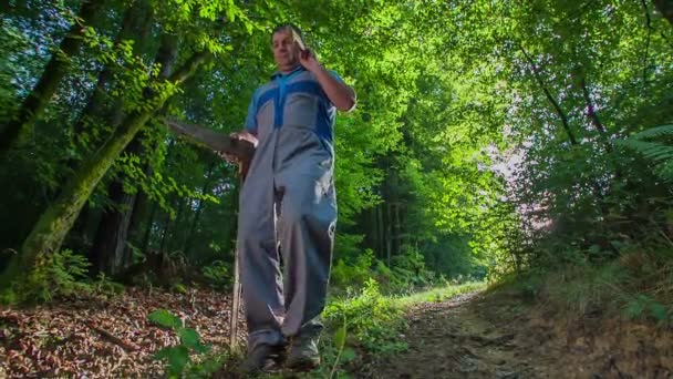 Le bûcheron aîné marche dans la belle forêt mixte. Il tient une hache très tranchante et un étrier vernier en bois .