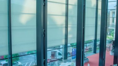 Cam la kaplı özel bir binada üst kat ve kalabalık bir yol manzarası.