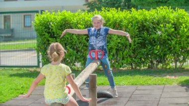 İki kız, okulun dışındaki bir salıncakta sallanırken uçuyormuş gibi davranıyorlar..