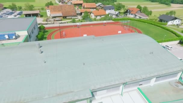 夏の日に大きな学校 スポーツコート 教会と美しい小さな町の空中映像 — ストック動画