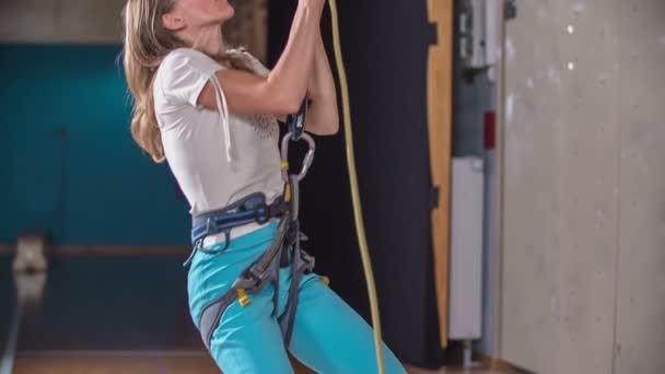 一位老师给一个学生更多的绳子 她正爬到学校体育馆的攀岩墙顶上 — 图库视频影像