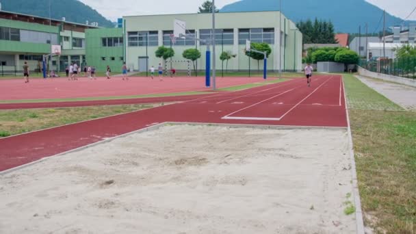 一个小男孩跑 做跳远 并降落在他的脚在沙 — 图库视频影像