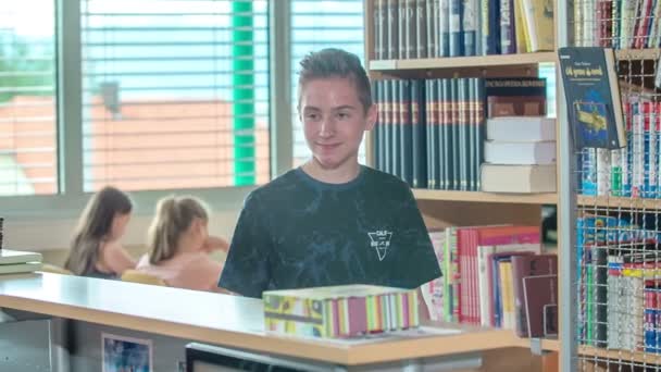 Ένα Αγόρι Χαιρετά Τον Βιβλιοθηκάριος Στη Βιβλιοθήκη Και Της Χαμογελάει — Αρχείο Βίντεο