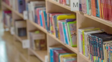 Kütüphanede bir rafta çocuklar için birçok kitap vardır. Bu bir okul kütüphanesi..