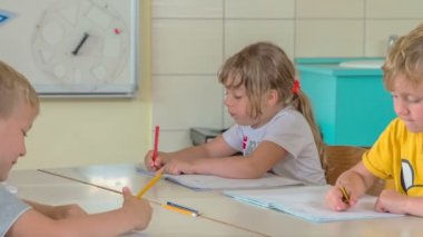 Öğrenciler çok dillidir. Bir egzersiz yapıyorlar ve bunu çalışma kitaplarına yazıyorlar..