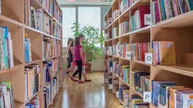 Genç kızlar bir kütüphanede ve yeni kitaplar alıyorsanız ve yeni şeyler öğreniyorlar.