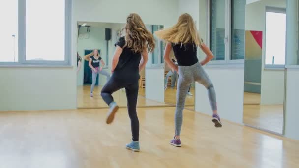 Дві Дівчини Практикуючих Танцювальні Ходи Перед Дзеркалом Шкільному Тренажерному Залі — стокове відео